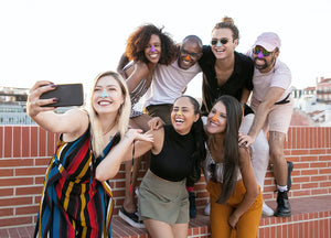 Group of 7 smiling people all wearing colorful Nöz, a zinc oxide, reef safe, biodegradable sunscreen while taking a selfie